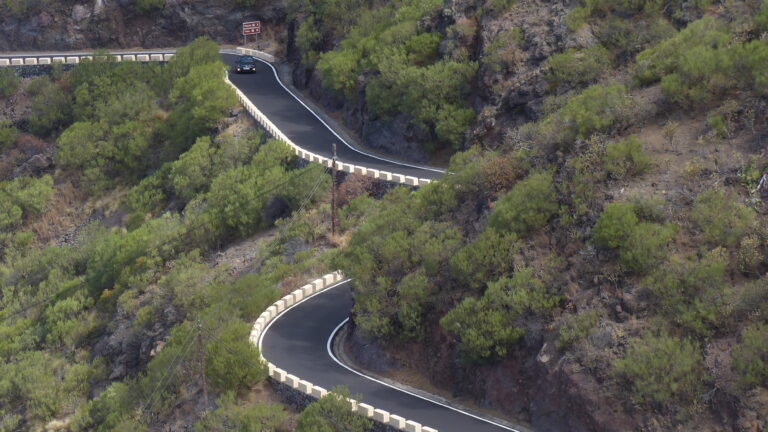 The TF-436 Masca road winding in hairpins down a green hillside in the Teno mountains