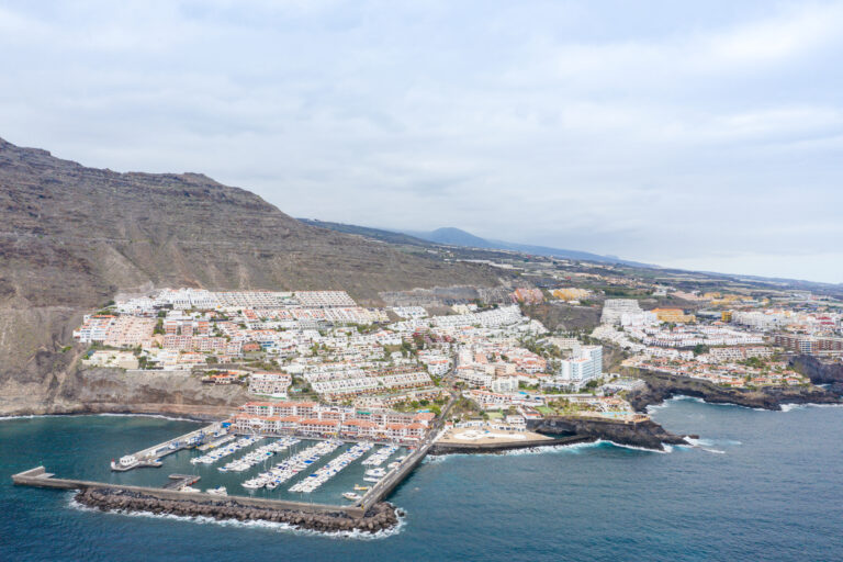 Aerial view of the Los Gigantes marina full of boats beneath the cliff wall